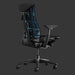 Ein Embody Gaming-Stuhl, leicht schräg von hinten betrachtet, so dass die cyanblaue Rückenlehne sowie ein Teil der Sitzfläche sichtbar sind. Der Stuhl steht vor einem schwarzen Hintergrund.