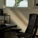 Nahansicht der Kante des Nevi Gaming-Schreibtischs, an dem ein Embody Gaming-Stuhl steht, mit einem Fenster im Hintergrund.